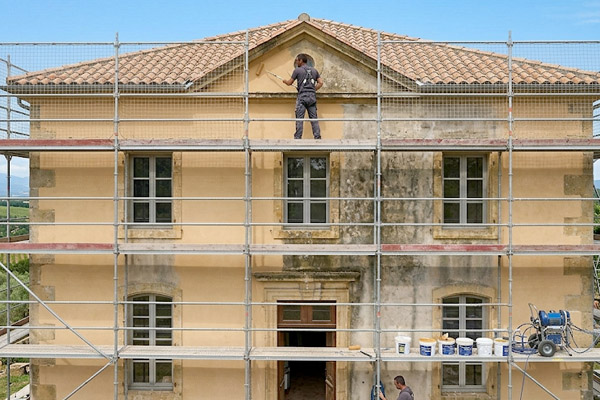 Peintre en bâtiment extérieur de l'entreprise Les Artisans du Toit Languidic appliquant une peinture hydrofuge siloxane sur la façade d'une maison en Bretagne
